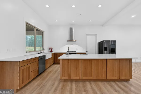 a large kitchen with stainless steel appliances granite countertop a sink a stove and a wooden floors