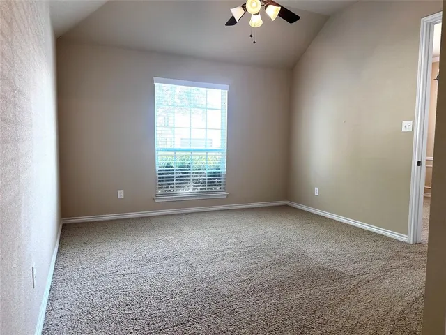 an empty room with a chandelier fan and windows