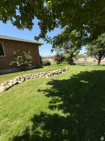 328 Heather Ridge Circle Sandy, UT 84070 - Photo 31 of 32 Expansive green lawn featuring a decorative river rock border