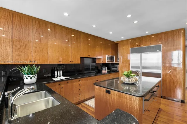 a kitchen with stainless steel appliances granite countertop a sink a counter top space cabinets and a couch