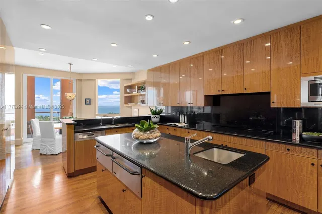 a kitchen with stainless steel appliances granite countertop a sink a stove and a wooden cabinets