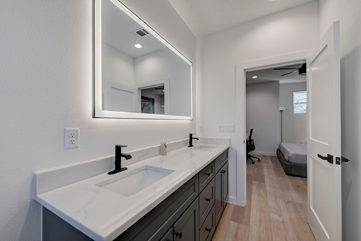 2220 Yellow Jacket Lane, Unit 1 Austin, TX 78741 - Photo 13 of 35 A well-appointed primary bathroom vanity boasts dual sinks with sleek fixtures and an illuminated mirror.