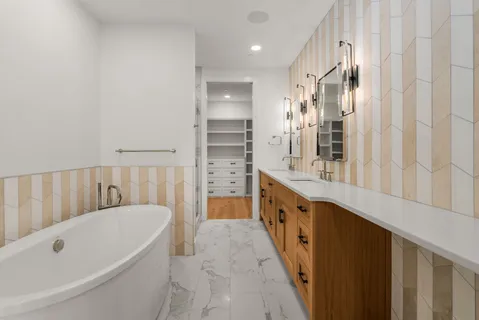 a bathroom with a tub a sink and a large mirror