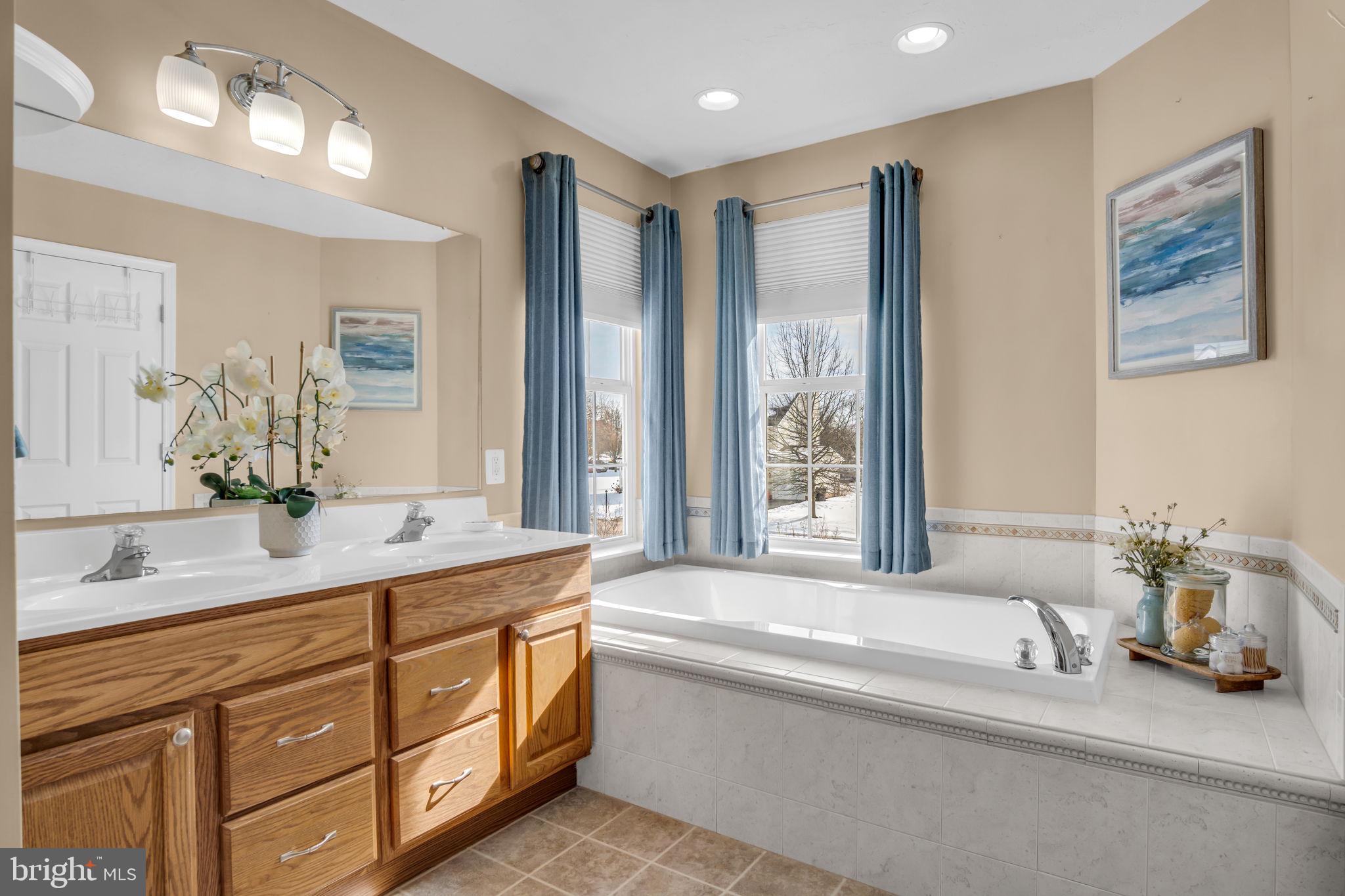 86 Barley Circle Hanover, PA 17331 - Photo 34 of 57 a spacious bathroom with double vanity a mirror a bathtub and a shower