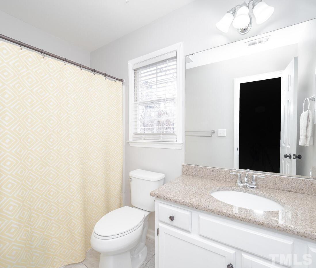 12105 North Exeter Way Raleigh, NC 27613 - Photo 25 of 27 a bathroom with a granite countertop sink a toilet and a mirror