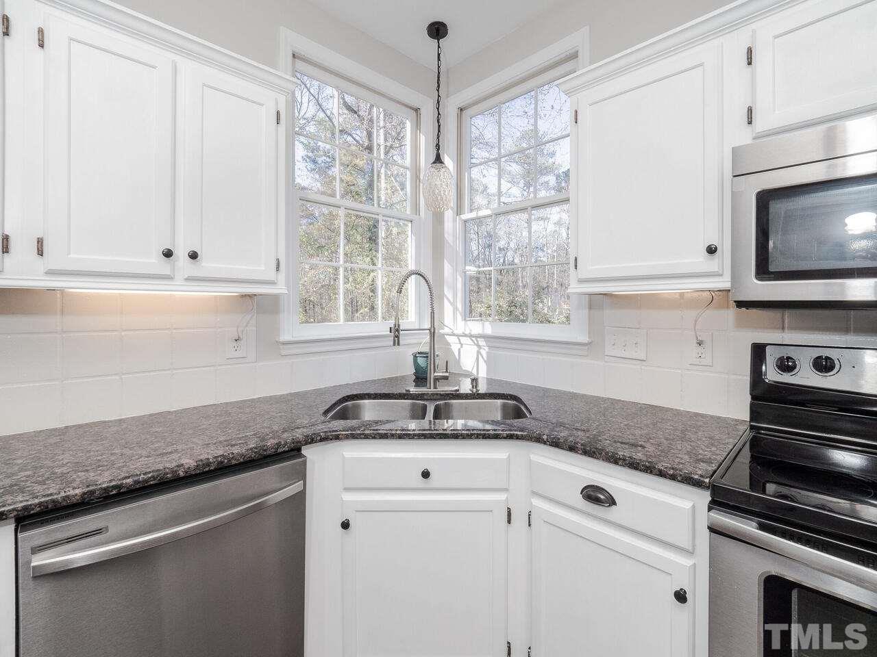 12105 North Exeter Way Raleigh, NC 27613 - Photo 10 of 27 a kitchen with stainless steel appliances granite countertop white cabinets and a window