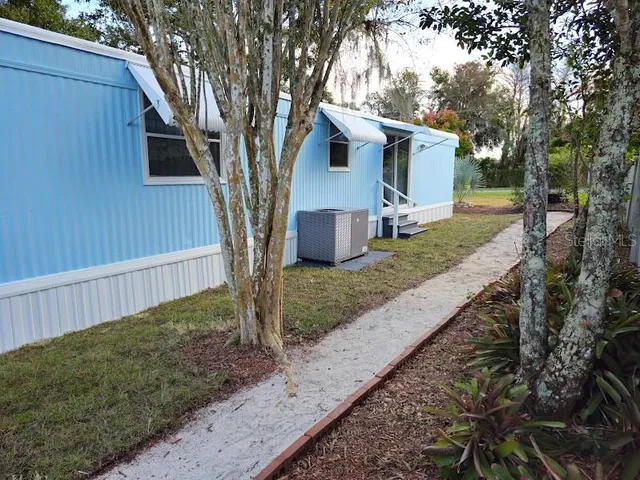 a view of a house with a yard and large tree