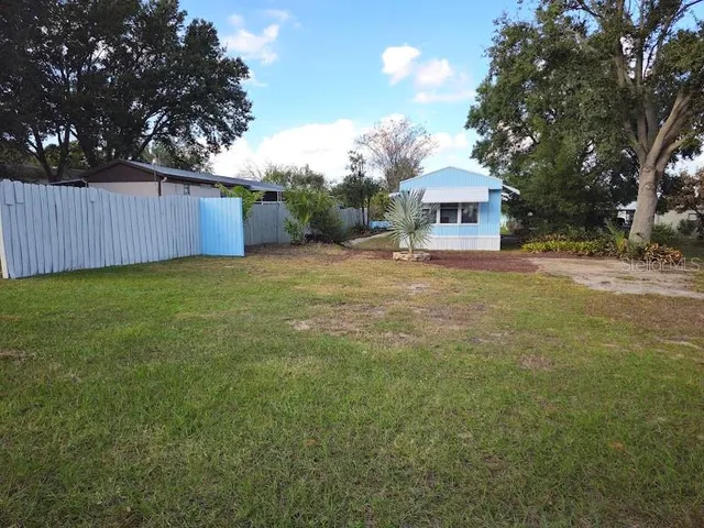 a view of a house with a yard and large tree