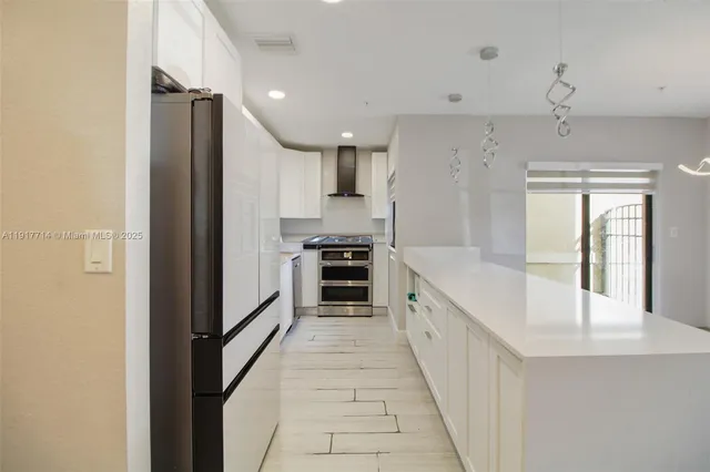 a large kitchen with a large counter top stainless steel appliances and cabinets