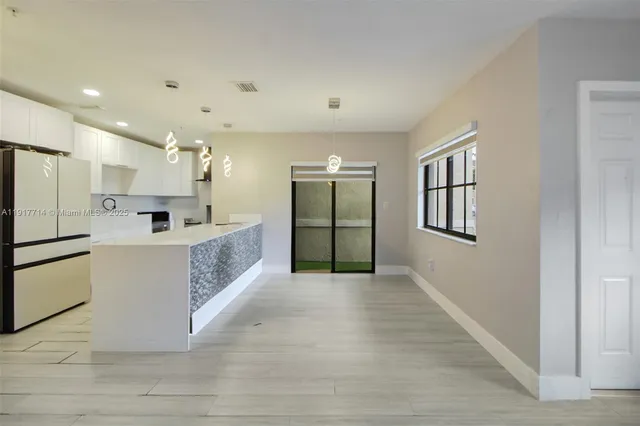 a large white room with kitchen island a sink wooden floor and a refrigerator