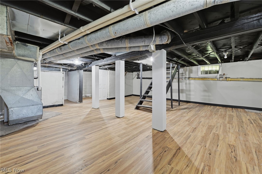 951 Bey Road Akron, OH 44312 - Photo 25 of 34 Expansive lower level featuring wood-finish flooring, white painted walls, exposed ceiling joists, and a utility staircase