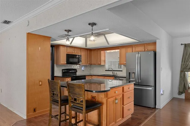 a kitchen with stainless steel appliances granite countertop a refrigerator a sink a stove top oven and a dishwasher