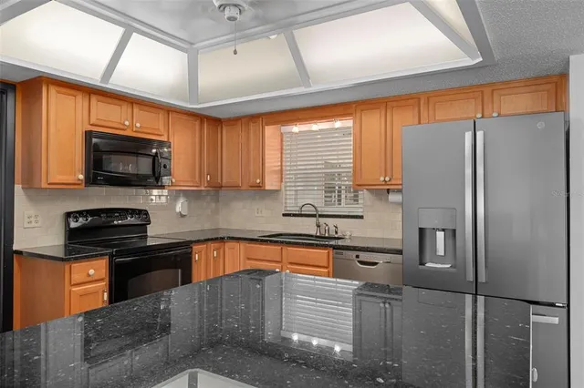 a kitchen with stainless steel appliances granite countertop a sink a stove and a refrigerator