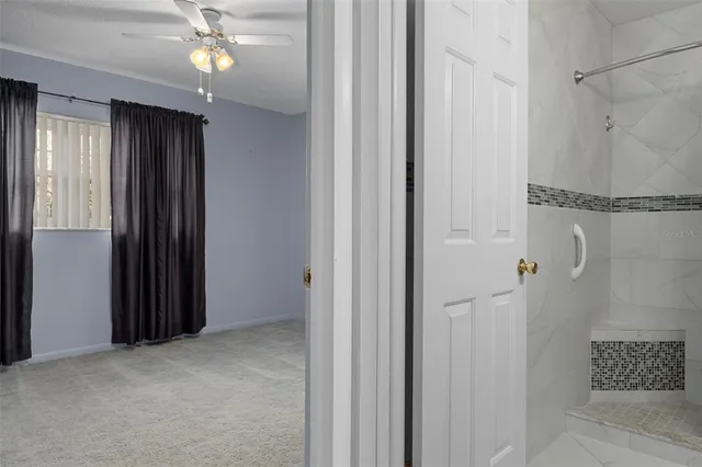 an empty room that has a window and a chandelier fan