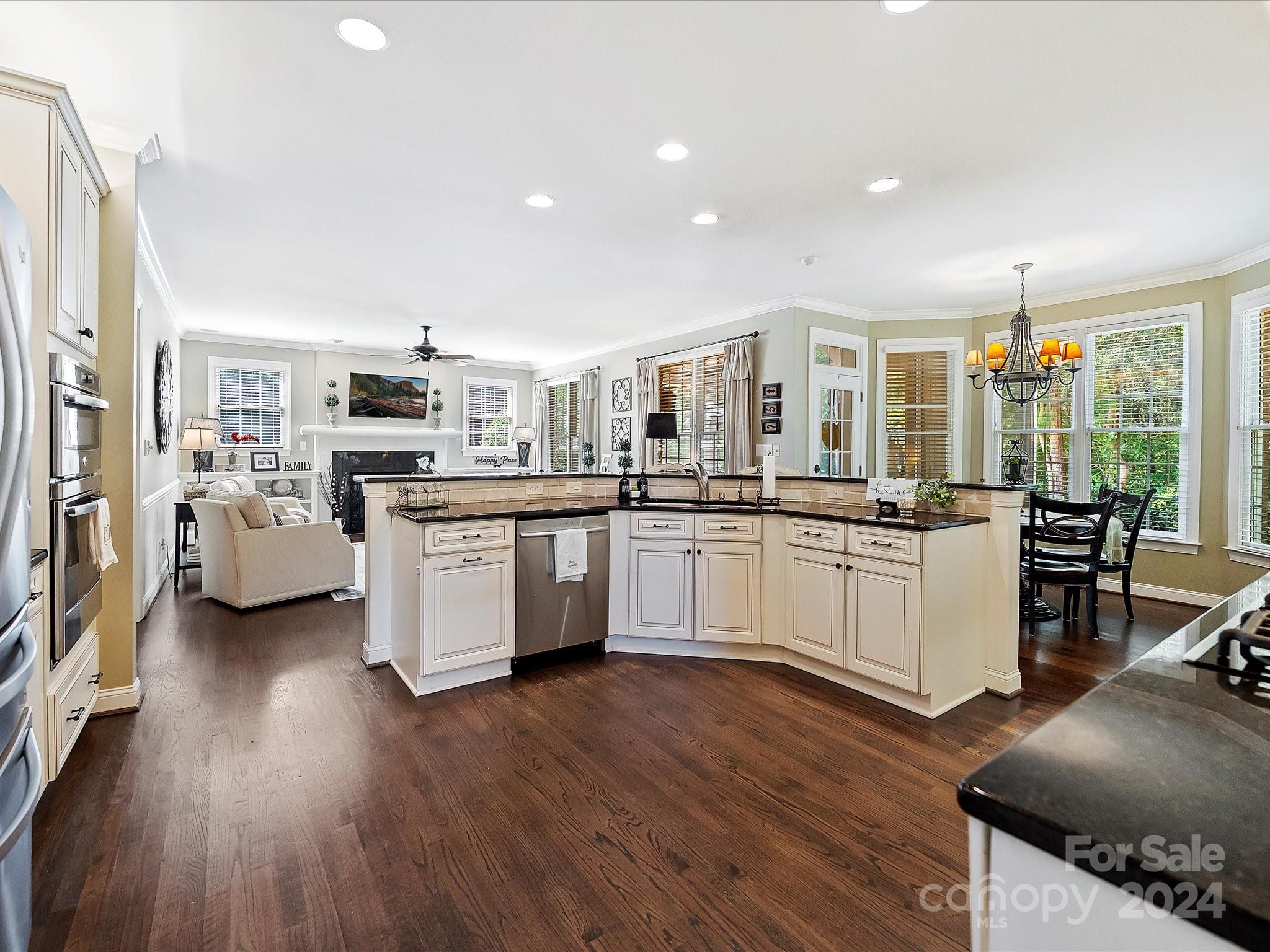 10309 Riesling Court Charlotte, NC 28277 - Photo 11 of 44 a kitchen with stainless steel appliances kitchen island granite countertop a stove top oven a sink a refrigerator with white cabinets and wooden floor