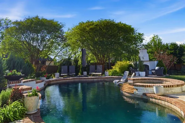 a view of swimming pool with lawn chairs and plants