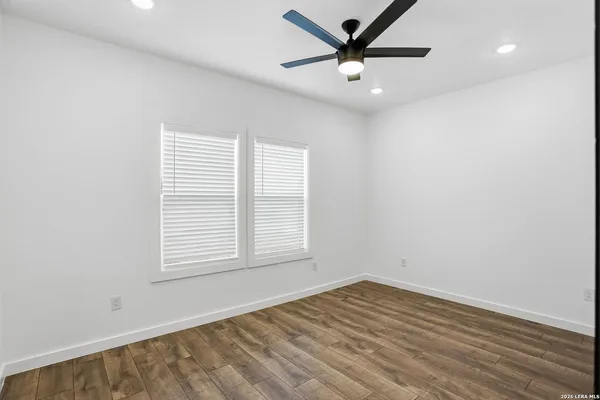 an empty room with wooden floor closet and windows