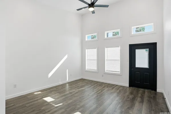 an empty room with wooden floor cabinet and windows