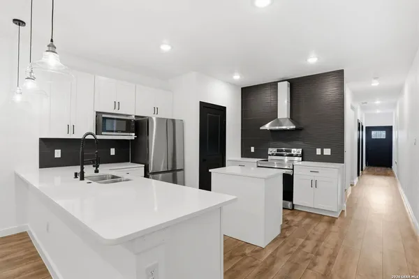 a kitchen that has a lot of white cabinets and stainless steel appliances