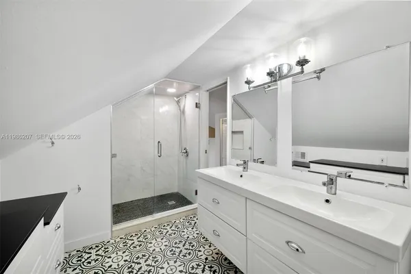 a bathroom with a double vanity sink a mirror and a shower