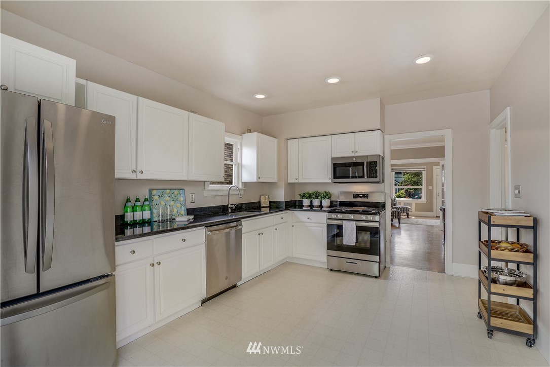 548 North 68th Street Seattle, WA 98103 - Photo 7 of 20 a kitchen with stainless steel appliances granite countertop a refrigerator and a stove top oven