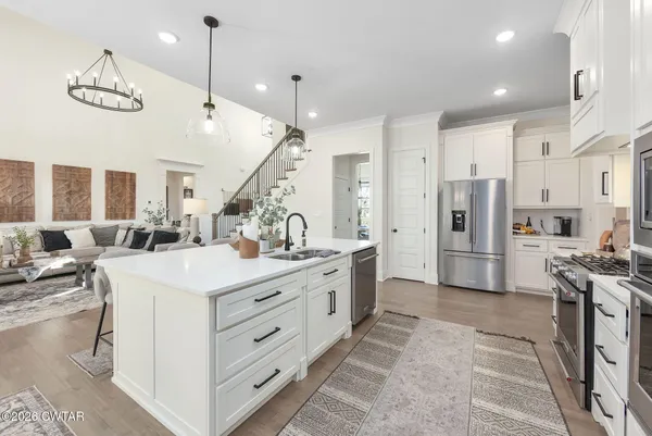 a large white kitchen with lots of counter space and chandelier