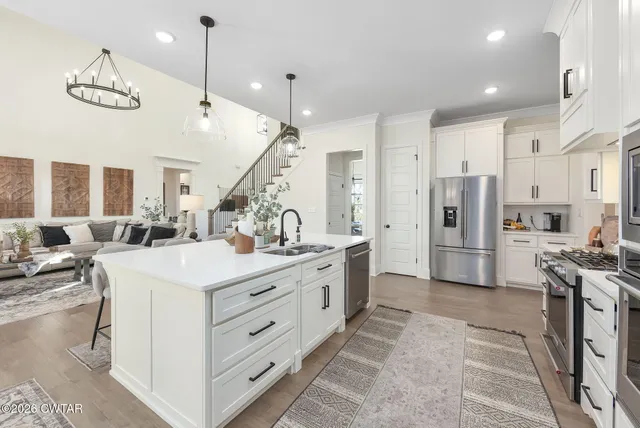 a large white kitchen with lots of counter space and chandelier