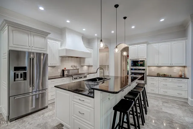 a view of an empty room and kitchen with wooden floor