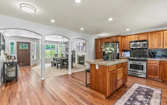a kitchen with stainless steel appliances granite countertop a stove oven and a dining table with wooden floor