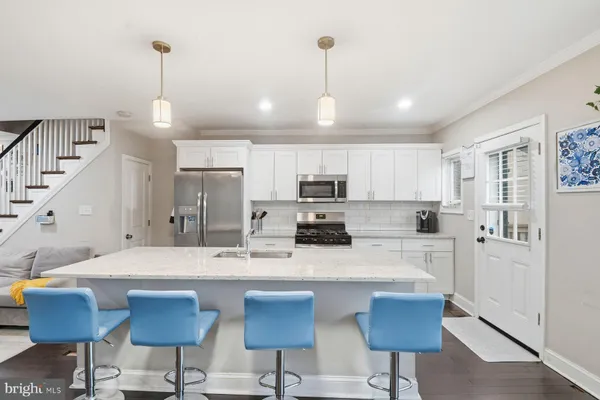 a kitchen with stainless steel appliances kitchen island granite countertop a dining table chairs refrigerator and sink