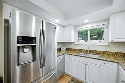 a kitchen with stainless steel appliances granite countertop a refrigerator and a sink