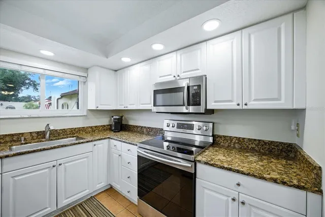 a kitchen with granite countertop white cabinets stainless steel appliances and a sink