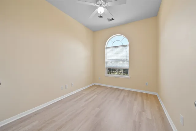 an empty room with a window and ceiling fan