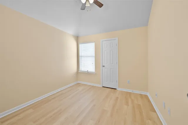 an empty room with a window and a ceiling fan