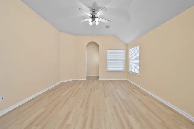 a view of empty room with wooden floor and fan