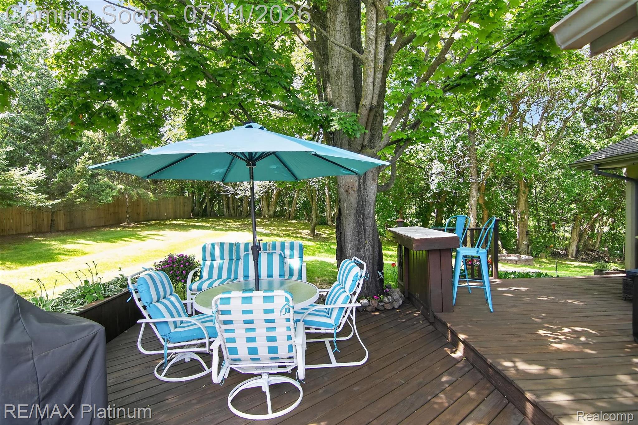 13365 North Territorial Road Gregory, MI 48137 - Photo 41 of 52 Spacious wood deck featuring an integrated bar with seating, a large shade umbrella, and mature trees