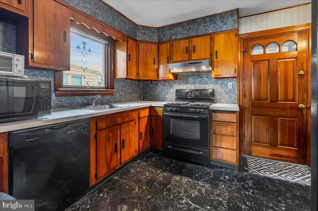 a kitchen with stainless steel appliances granite countertop wooden cabinets a stove top oven a sink and dishwasher next to a window