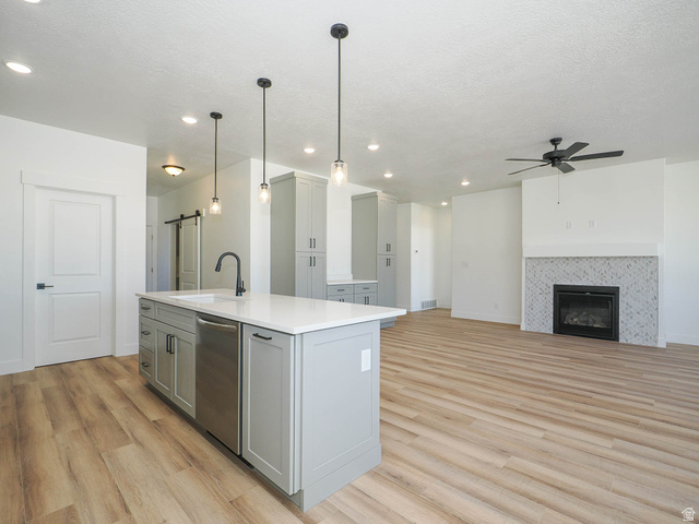3938 North Wood Road Eagle Mountain, UT 84005 - Photo 55 of 55 Kitchen with a barn door, gray cabinetry, a center island with sink, light wood-style flooring, and open floor plan
