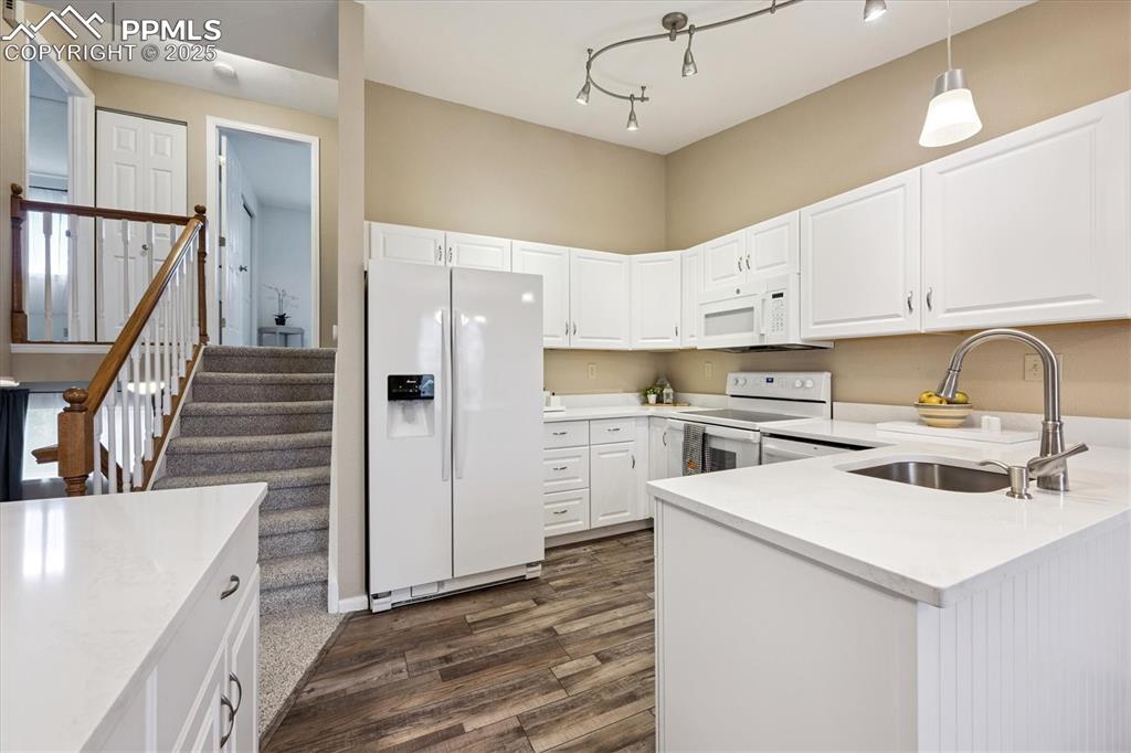704 Madison Way Bennett, CO 80102 - Photo 10 of 29 a kitchen with white cabinets and white appliances