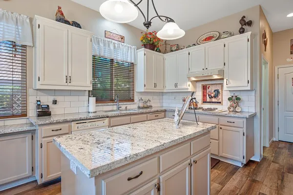 a kitchen with kitchen island granite countertop a sink a counter space appliances and cabinets