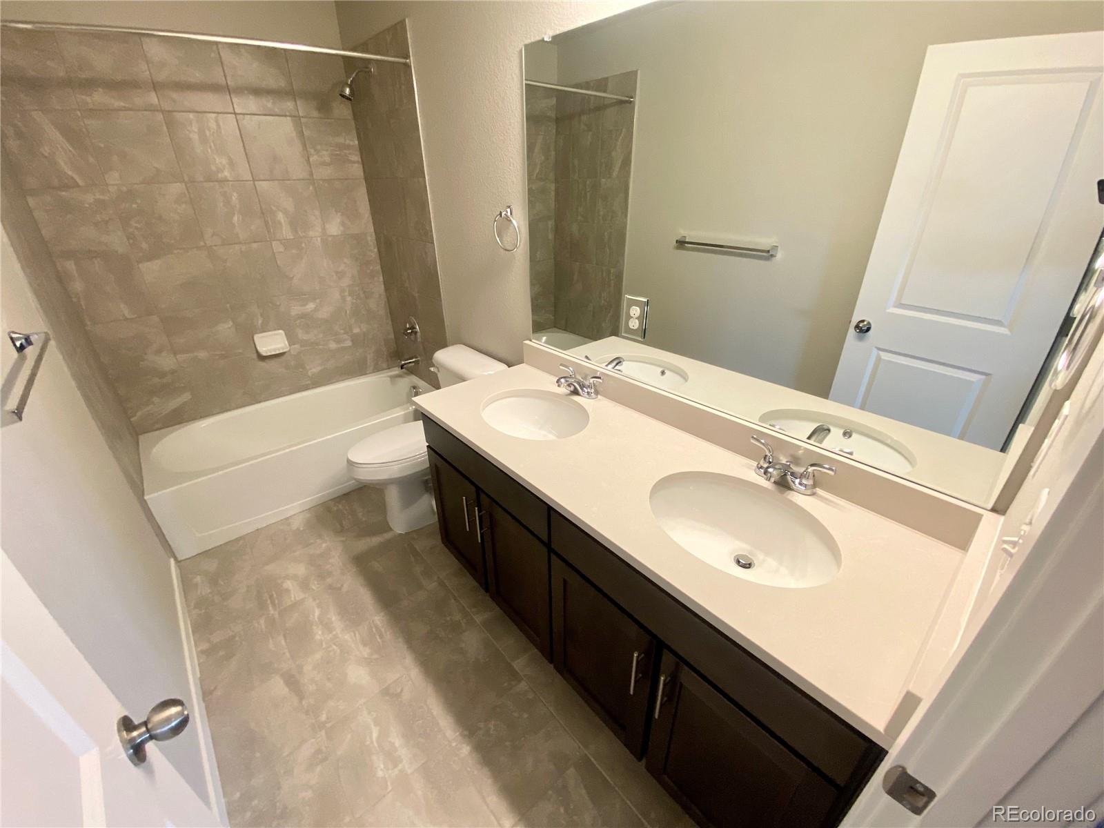 517 Ryan Avenue Fort Lupton, CO 80621 - Photo 12 of 21 a bathroom with a double vanity sink a toilet and a bathtub