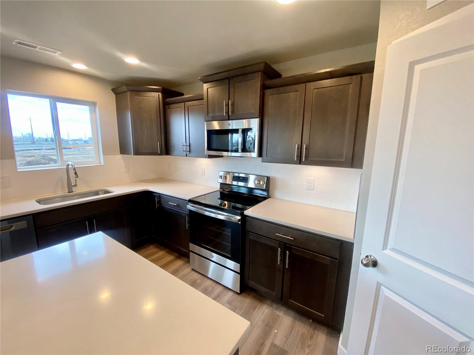 517 Ryan Avenue Fort Lupton, CO 80621 - Photo 3 of 21 a kitchen with granite countertop a stove and a sink
