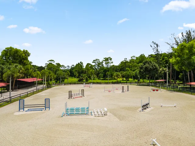 a swimming pool with outdoor seating and trees in the background