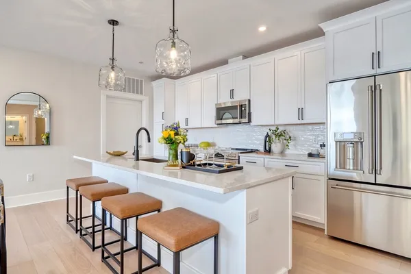 a kitchen with stainless steel appliances granite countertop a stove a refrigerator a kitchen island a stove a dining table and chairs with wooden floor