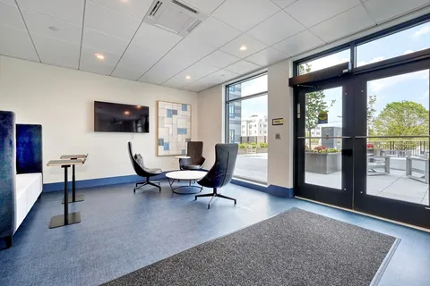 a living room with furniture floor to ceiling window and a flat screen tv