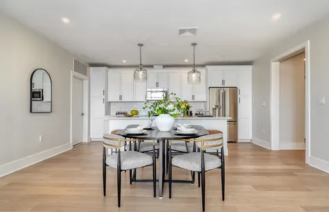 a kitchen with stainless steel appliances granite countertop a table chairs and a refrigerator