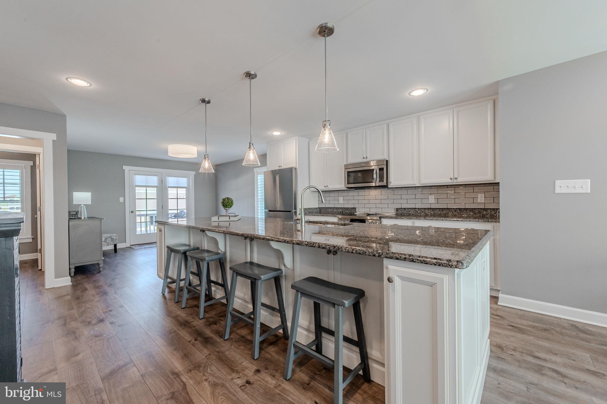 100 Anglers Road, Unit A4 Lewes, DE 19958 - Photo 22 of 57 a kitchen with stainless steel appliances granite countertop a stove top oven a refrigerator a sink and a dining table with wooden floor