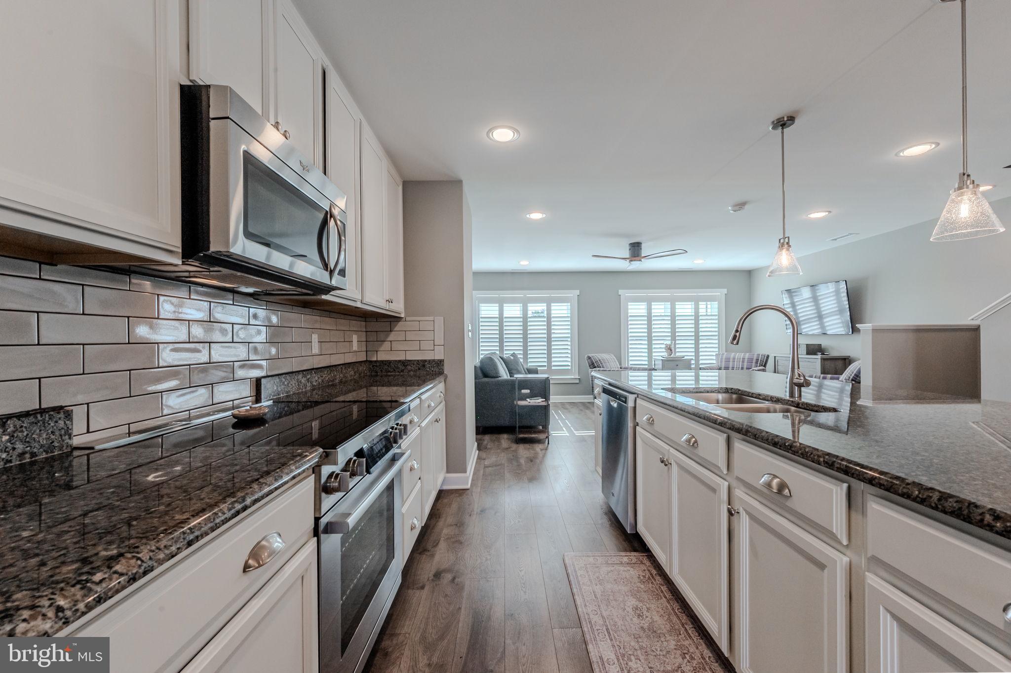 100 Anglers Road, Unit A4 Lewes, DE 19958 - Photo 24 of 57 a kitchen with stainless steel appliances granite countertop a stove a sink and a microwave
