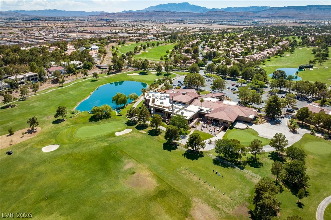 20 Innisbrook Avenue Las Vegas, NV 89113 - Photo 27 of 39 An aerial perspective reveals the lush golf course, shimmering lake, and a grand clubhouse set against a distant mountain range.