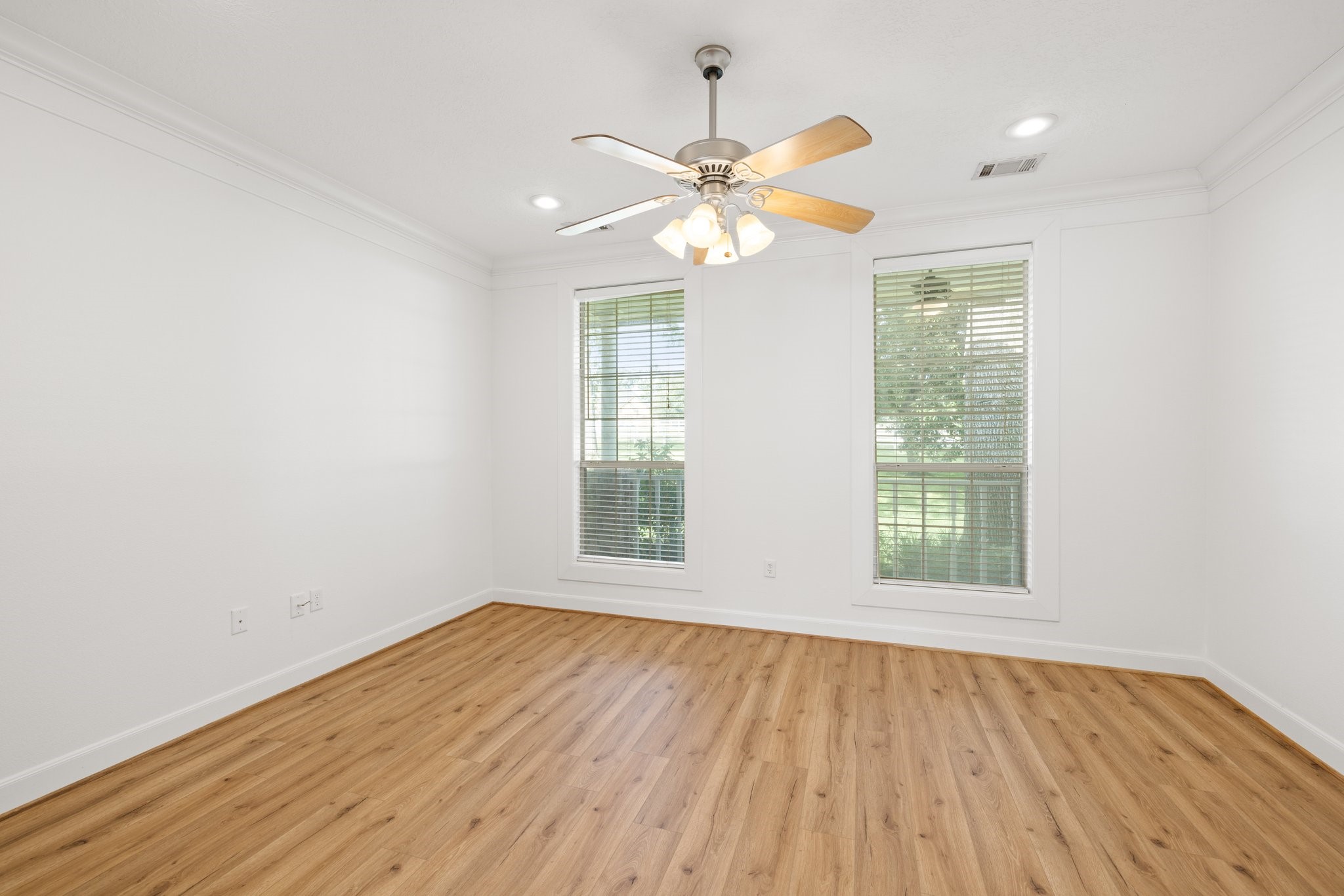 34310 High Point Drive Magnolia, TX 77355 - Photo 13 of 48 Expansive primary bedroom with elegant vinyl plank flooring, a ceiling fan, and serene outdoor views.